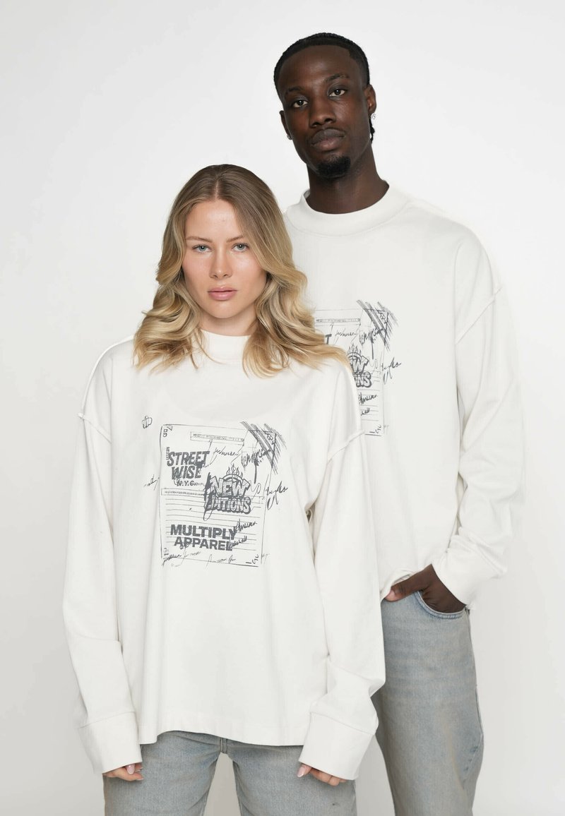 Witte shirts met lange mouwen hebben een grafische opdruk met tekst en tekeningen. De stof is zacht, met een verlaagd schouderlijn en een losse pasvorm.