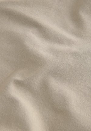 Beige tyg med en slät textur, som visar mjuka veck och en subtil glans. Materialet verkar vara bomull eller en bomullsmix.