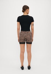 Svart ribbestrikket kortermet topp kombinert med leopardmønstrede shorts med blonder. Antrekket er laget for å sitte tett rundt midjen.