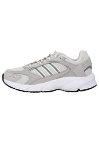 Scarpa sportiva grigia chiara con tomaia in mesh e sintetico, accentuata da dettagli bianchi, tre strisce metalliche sul lato e suola nera texture.