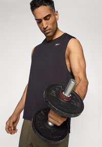 T-shirt de sport sans manches noir, bras musclé soulevant un haltère avec des poids gris et noir, arrière-plan uni.