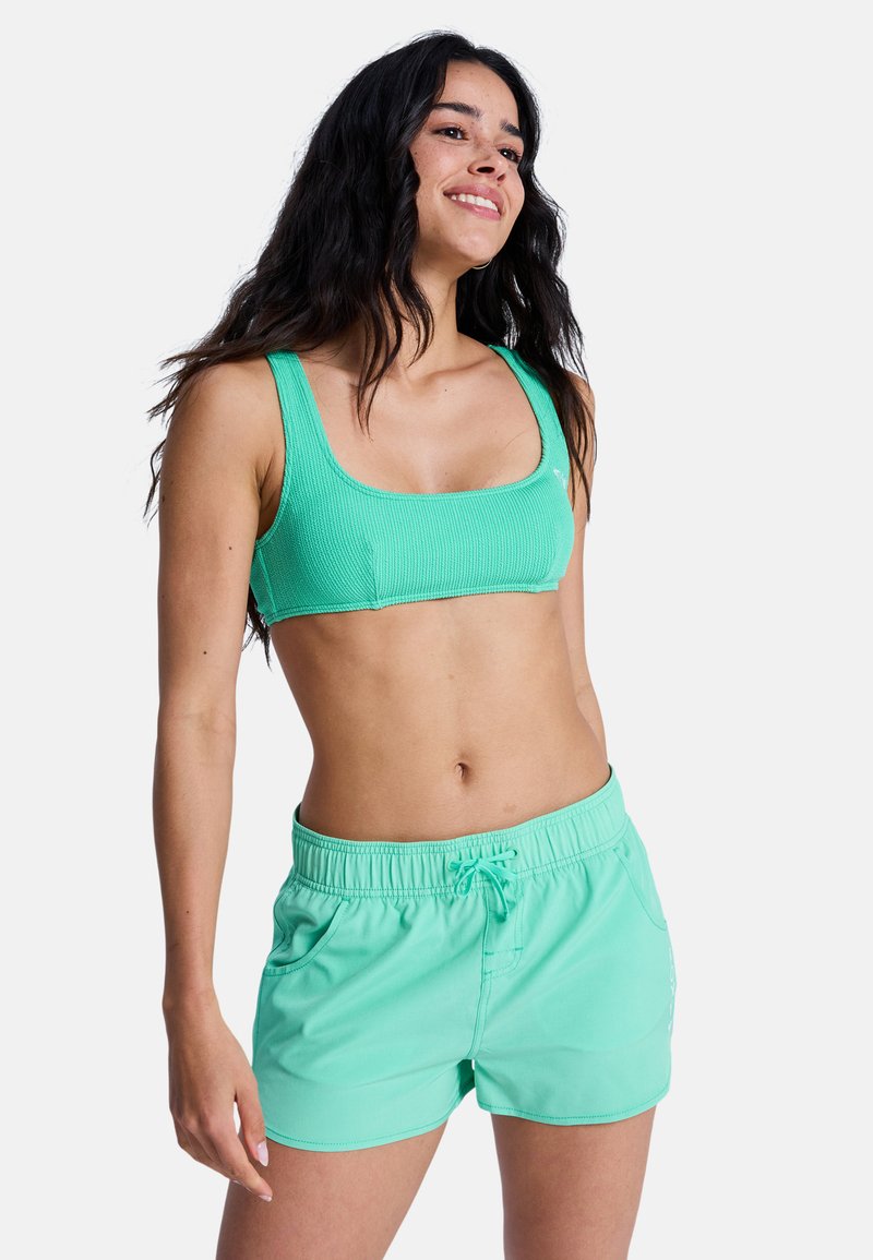 Haut de bikini côtelé vert menthe avec un décolleté carré, assorti à un short de bain coordonné doté d'une ceinture élastique et de poches latérales.