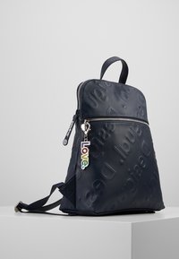 Sac à dos marine en matériau texturé avec logo en relief. Doté d'un dessus zippé et d'un charm "Love" coloré attaché.