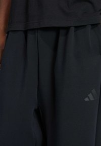 Black athletic shorts made from a soft, smooth fabric. Features a subtle textured Adidas logo in the lower corner and an elastic waistband.