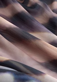 Tissu translucide avec un tissage texturé, présentant un motif dégradé de rose doux, violet et teintes foncées, créant un effet de couches.