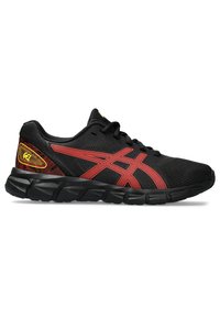 Baskets de sport noires avec une tige en mesh, dotées d'accents rouges et d'un logo distinctif. La semelle est texturée pour une traction et une flexibilité optimales.