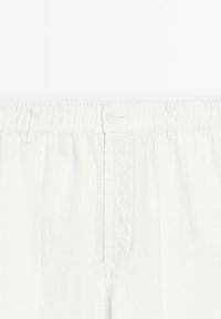 Pantalons en lin blanc avec une taille élastique, un bouton de fermeture et des poches avant avec une texture subtile. Design simple et épuré.