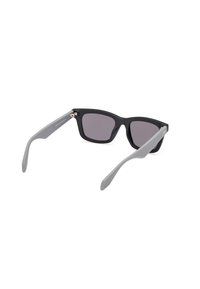 Black plastic sunglasses with gray rubberized temple tips, square frame, and dark tinted lenses. Features a zigzag pattern on the temple tips.