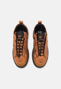 Brune lædersneakers med et struktureret design, logo detaljer, sorte snører og en gummisål med en kontrasterende tan tåkappe.