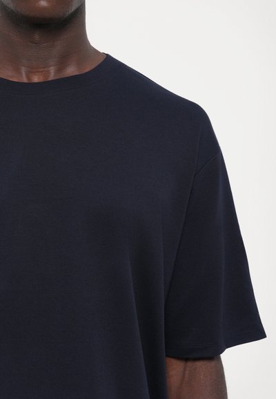 Ναυτικό μπλε μπλουζάκι με στρογγυλή λαιμόκοψη, κατασκευασμένο από μαλακό ύφασμα. Διαθέτει κοντά μανίκια και άνετη εφαρμογή, με λεία και ομοιόμορφη υφή.