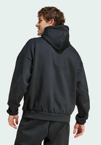 Black hooded sweatshirt with a relaxed fit, textured fabric, ribbed hem, and cuffs; features a kangaroo pocket and a lined hood.