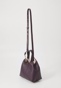 Borsa a tracolla in pelle viola con finitura texturizzata, forma arrotondata, tracolla staccabile e dettagli in hardware dorato.