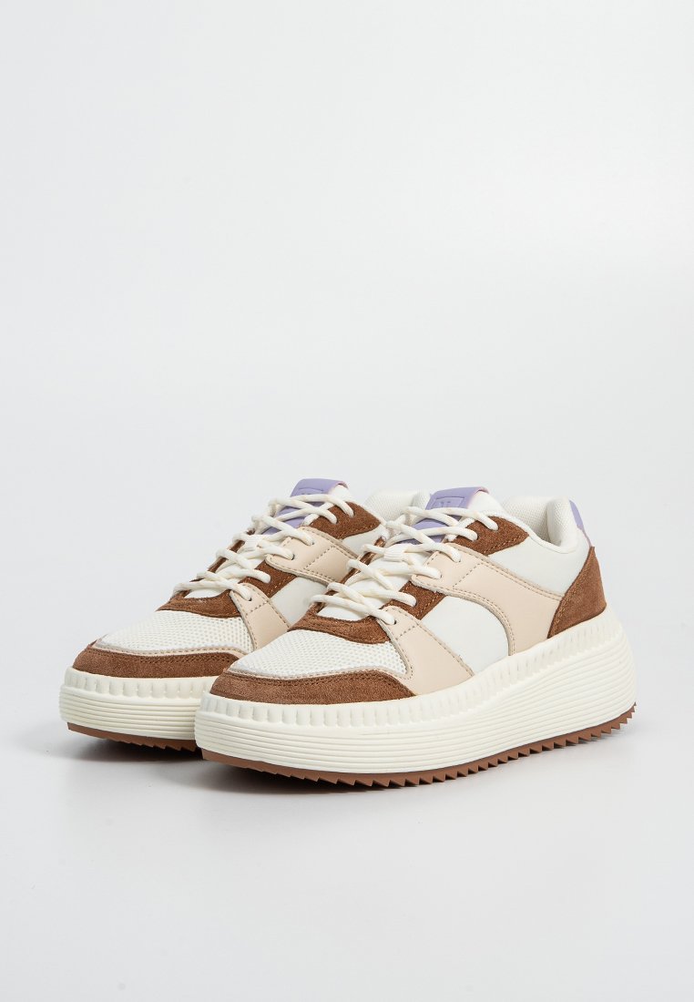 Sneakers con una combinazione di rete crema e suede marrone, dotati di una suola spessa bianca, lacci tondi e un accento viola sulla linguetta.
