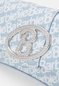 Vaaleansininen farkkuklipsilaukku, jossa on toistuva "Barbie"-tekstikuvio, koristeltu hopeisella logolla, joka on koristeltu kirkkailla strasseilla.