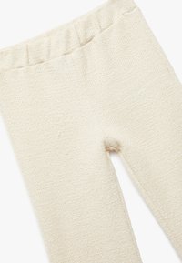 Vaaleanbeige neulottuja legginssejä elastisella vyötäröllä. Tekstuurin pinta on hieman koholla ja kudottu. Yksinkertainen muotoilu, ilman lisäkuvioita tai yksityiskohtia.