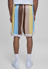 Večbarvne športne hlače z navpičnimi črtami v rjavi, modri, rumeni in bež barvi, z belim elastičnim pasom in obrobjem.