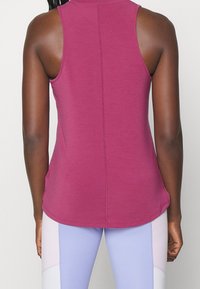 Bezrękawnik w kolorze fuksji z zaokrąglonym dołem, posiadający centralny szew z tyłu oraz gładką, lekką teksturę tkaniny.