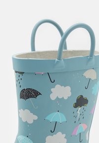 Conteneur bleu avec une finition texturée, présentant un motif d'ombrelle et de nuages. Il a deux poignées assorties et un intérieur doublé en tissu.