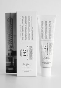 Hvit tube med Dr. Althea barrierekrem med hevet etikett og svart tekst, ved siden av en eske med svart-hvitt illustrasjon og tekst.