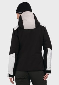 Schwarze und hellgraue wasserdichte Jacke mit Kapuze, weißen Akzenten an Schultern und Ärmeln sowie verstellbaren Manschetten. Strukturierter Stoff.