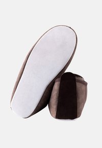 Pantofole in suede marrone con suola bianca liscia, caratterizzate da un accento marrone scuro sul tallone e un design della punta arrotondato.