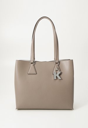 Torba typu tote z taupe skóry z podwójnymi uchwytami i srebrnym zawieszonym literą "K" przy prawym górnym uchwycie.