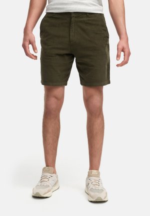 Olivgrüne Shorts aus weichem Stoff mit geradem Schnitt, flachem Bund und Seitentaschen, kombiniert mit hellen Sportschuhen.