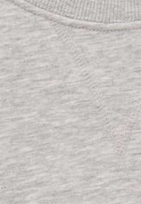 Tissu gris clair en gros plan avec un col côtelé et un détail en forme de V cousu sous l'encolure.
