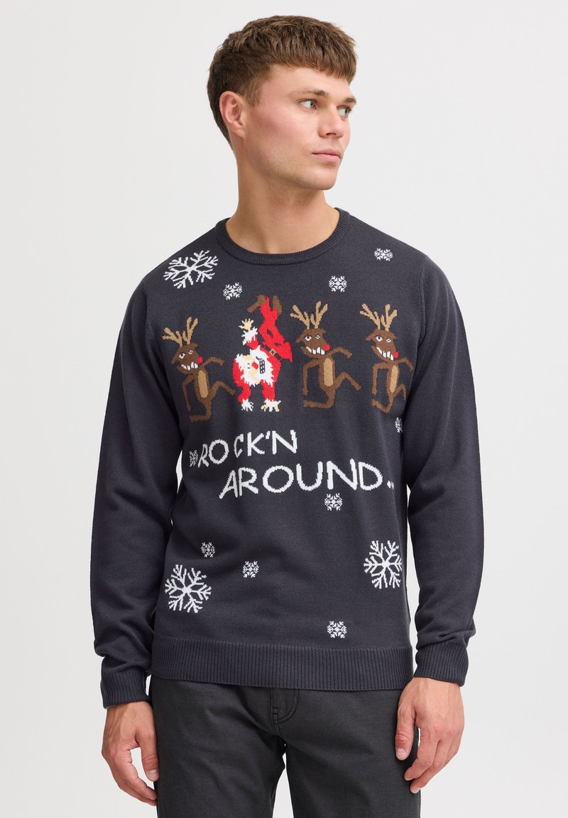 Dunkelgrauer Pullover mit Rentier- und Schneemann-Muster, weißen Schneeflocken und dem Text "ROCK'N AROUND" in fetter Schrift. Stricktextur, lange Ärmel.