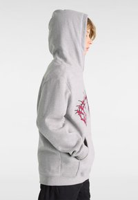 Sudadera con capucha de color gris claro, con un bolsillo tipo canguro, que presenta un diseño gráfico rojo en la parte delantera y una tela suave y texturizada.