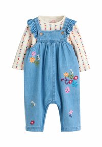 Farmer overál fodros pántokkal, gombokkal és színes virágmintával. Csíkos, hosszú ujjú pólóval párosítva.