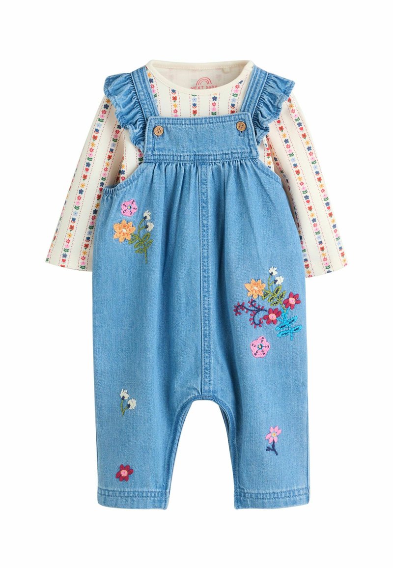 Farmer overál fodros pántokkal, gombokkal és színes virágmintával. Csíkos, hosszú ujjú pólóval párosítva.