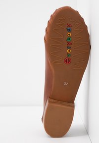 Chaussures marron avec une semelle en caoutchouc texturée, arborant le mot "tout le monde" en lettres colorées et une empreinte de taille "37".