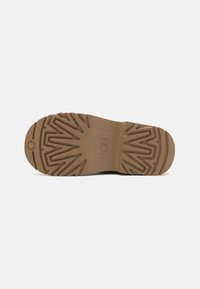 Suela de zapato de material de goma marrón texturizado, con un patrón en zigzag y un diseño circular en el talón, que proporciona tracción y estabilidad.