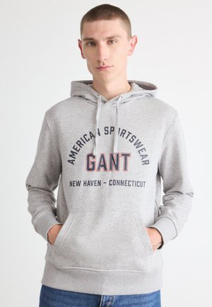 Sudadera con capucha gris fabricada en un material suave, con un logotipo frontal que dice "GANT", un bolsillo tipo canguro y puños de canalé.