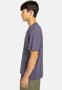 T-shirt a maniche corte, collezione girocollo, di colore viola scuro, realizzato in cotone morbido, con una vestibilità rilassata e dettagli di cucitura minimi.