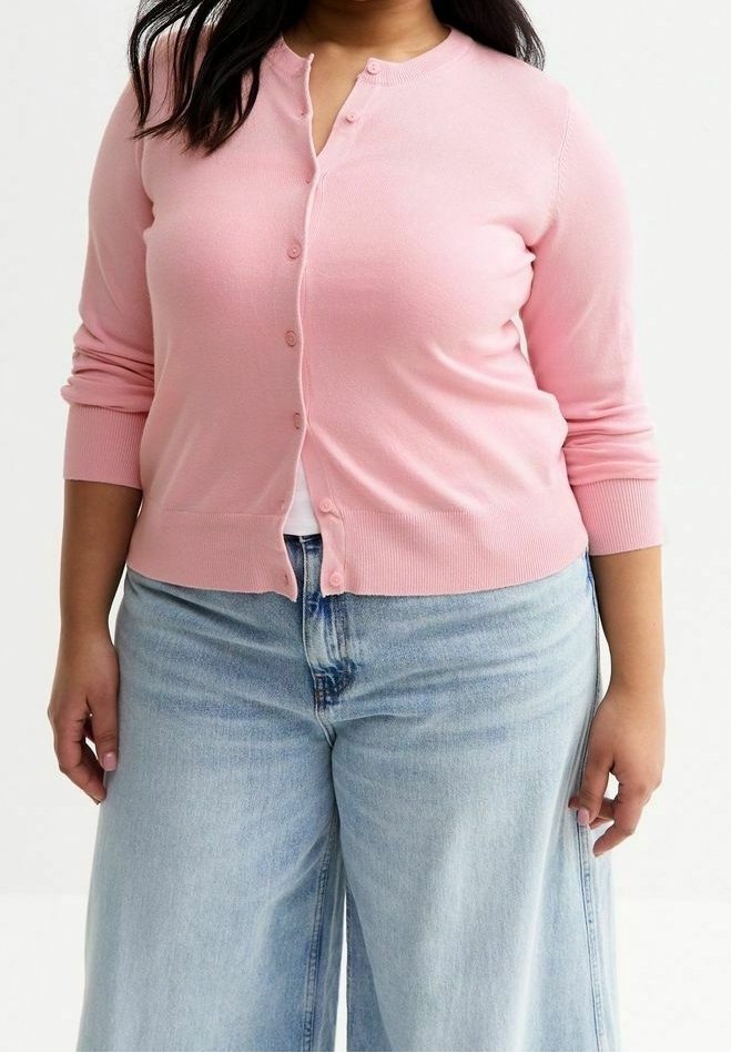 Světle růžová kardigan na knoflíky vyrobený z vroubkované pleteniny; má kulatý výstřih a dlouhé rukávy, nošený přes světle modré široké džíny.