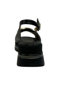 Sandalo nero con design a cinturino, dotato di una suola a piattaforma testurizzata e una fibbia metallica. Stile minimalista con finitura in pelle liscia.