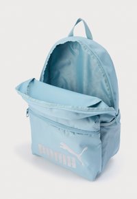 Ανοιχτό μπλε υφασμάτινο σακίδιο πλάτης με κεντρικό διαμέρισμα με φερμουάρ και μπροστινή τσέπη, διακοσμημένο με μεγάλο λευκό λογότυπο Puma και λεπτομέρεια από δίχτυ στα πλαϊνά.