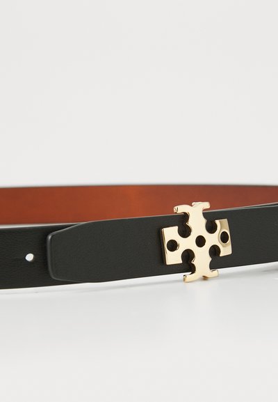 Černý kožený opasek se zlatou sponou, která má design kříže a kruhové výřezy. Rubová strana je hnědá.