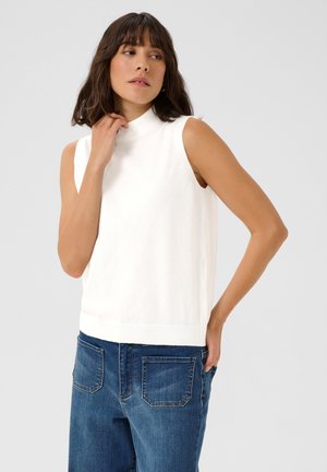 Haut en tricot sans manches blanc avec un col montant, présentant une texture douce et une coupe droite, associé à un jean en denim bleu.