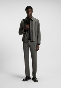 Gray jacket with a standing collar, textured fabric, and elasticized hem, paired with matching gray trousers and black shoes.