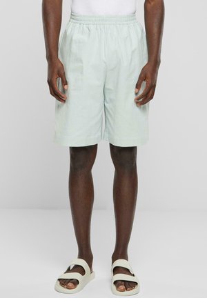 Ljusgröna shorts i lättviktstyg, med resårmidja och sidofickor, kombinerade med beige sandaler.