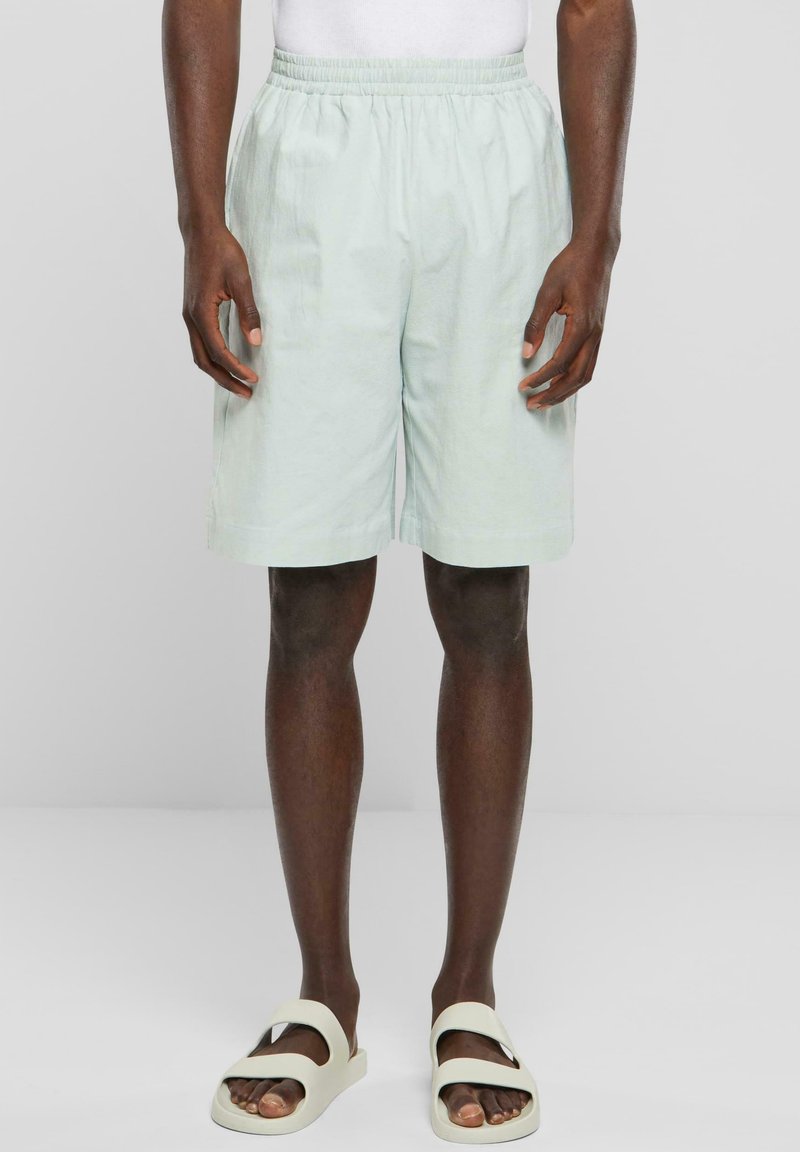 Ljusgröna shorts i lättviktstyg, med resårmidja och sidofickor, kombinerade med beige sandaler.