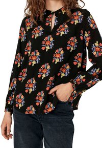 Svart långärmad blus med blommönster i röd, gul och blå. Har rund halsringning med ett nyckelhål och en avslappnad passform.