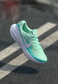 Lichte hardloopschoen in mintgroene mesh met witte accenten, voorzien van een ronde neus, een gevoerde zool en een vetersluiting.