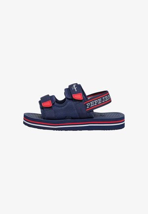 Laivastonsininen avokärkinen sandaali, jossa säädettävät punaiset ja laivastonsiniset hihnat, verkkokangas ja raidoitettu pohja valkoisella, punaisella ja laivastonsinisellä värillä.