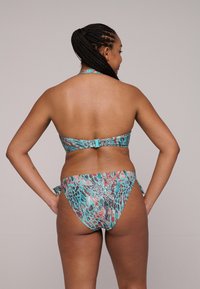 Bikini met een turquoise, koraal en zwart dierenprint. Haltertop met een sluiting op de rug; de onderkant heeft zijknoopjes en een vergelijkbaar patroon.