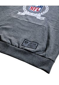 Grauer Sweatshirt mit einer Fronttasche, versehen mit einem NFL-Logo und einem "RECOVERED"-Etikett mit Pflegehinweisen entlang des unteren Saums.