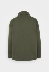 Pulóver verde oliva con cuello y mangas largas, de corte holgado, fabricado en un material suave y con un diseño simple y limpio.